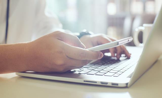 Person using a phone and laptop simultaneously