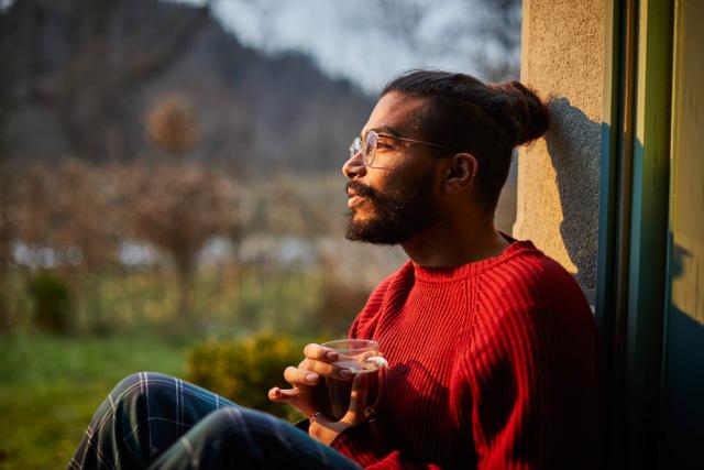 Man holding beverage while looking out a window