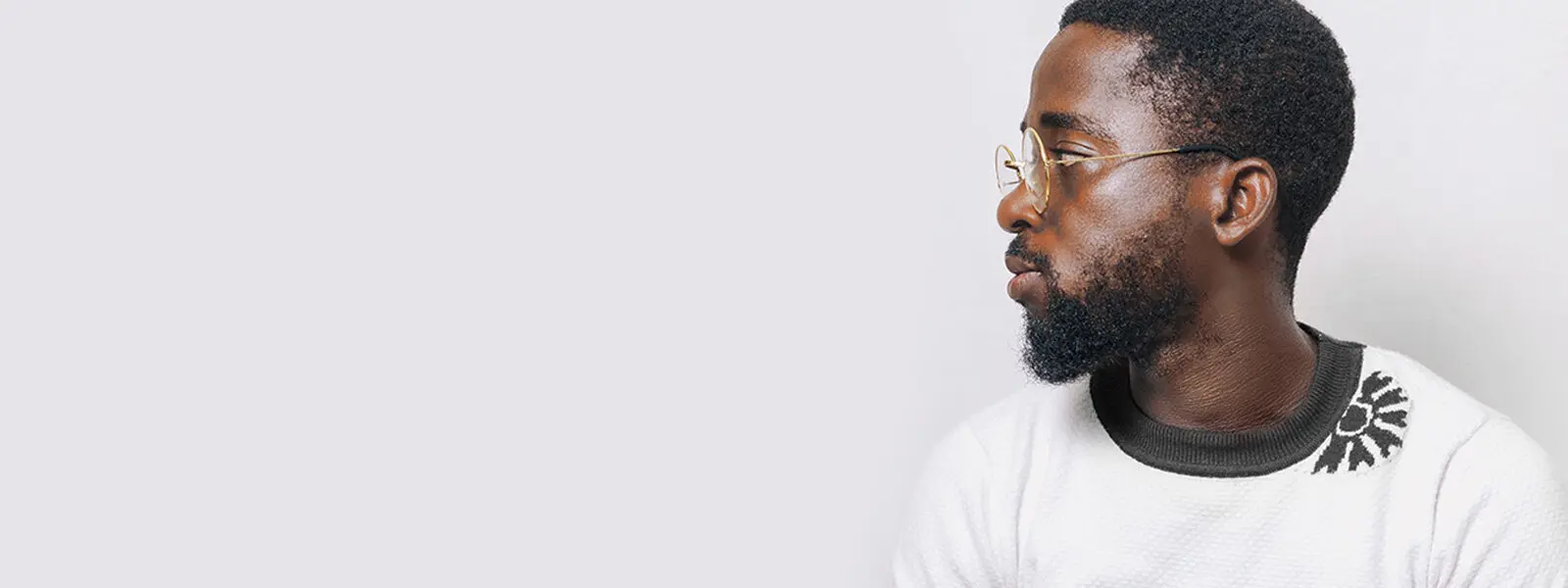 Bannière affichant un jeune homme barbu, portant des lunettes et regardant par-dessus son épaule droite, à côté de l’énoncé ROGAINE®