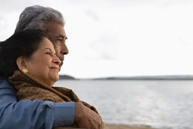 Un couple âgé enlacé au bord d’une plage