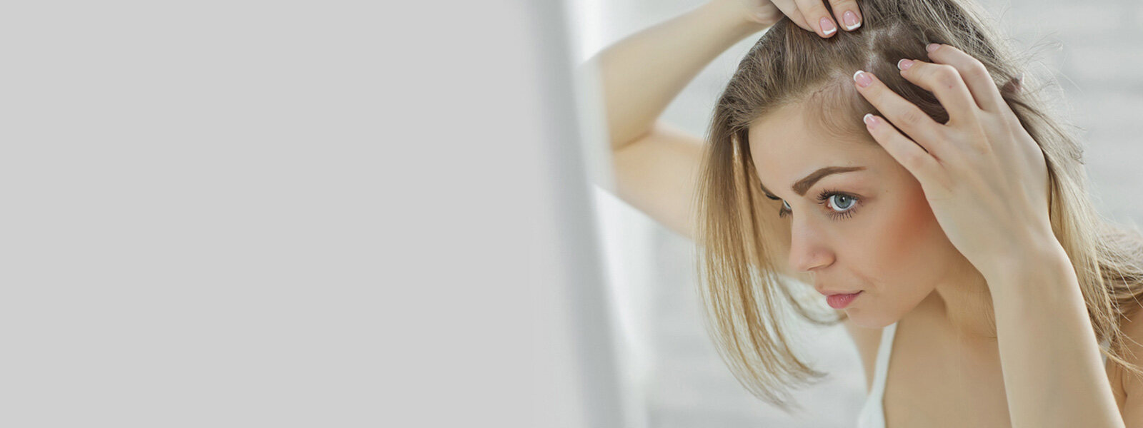 femme blonde qui inspecte sa perte de cheveux dans un miroir