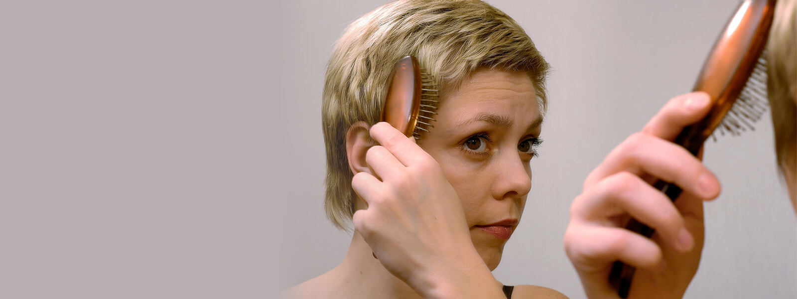 femme aux cheveux courts qui se brosse les cheveux amincis