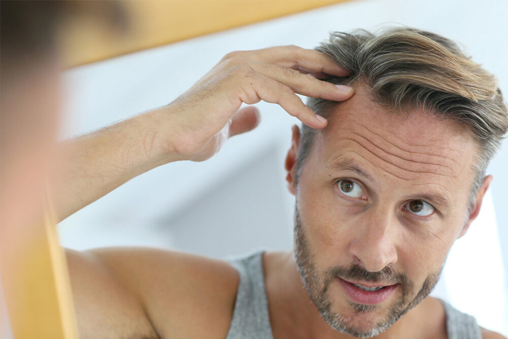 homme aux cheveux châtains qui passe la main sur ses tempes