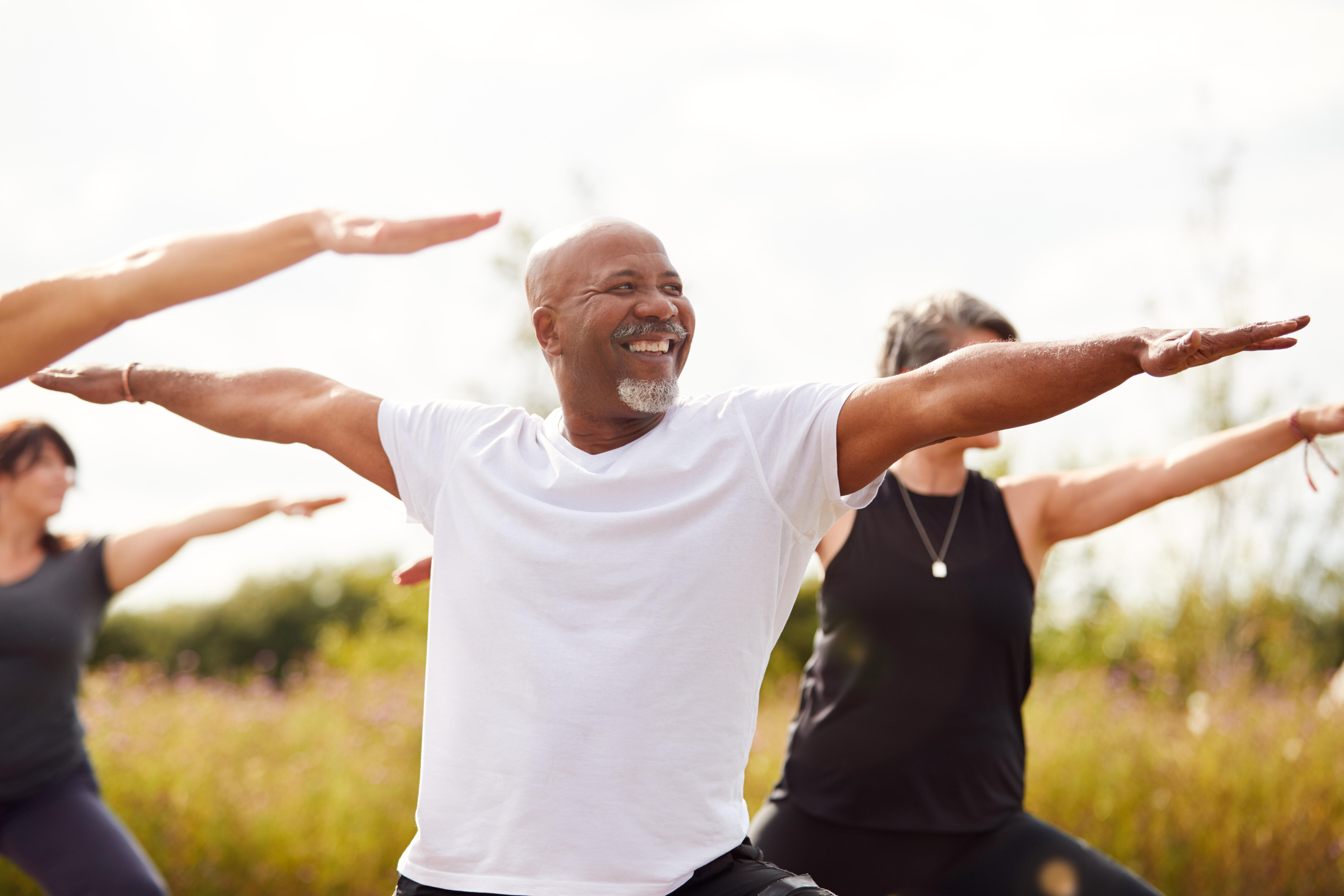 Man smiling brightly while participating in a group outdoor workout session. 