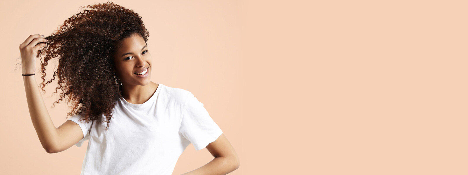 femme aux cheveux noirs bouclés vêtue d'un t-shirt blanc