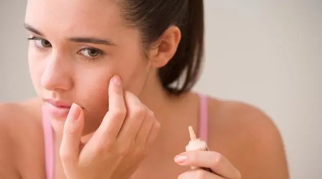 Woman applying corrective treatment to her face