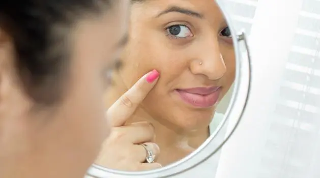 Woman looking at her skin in a mirror