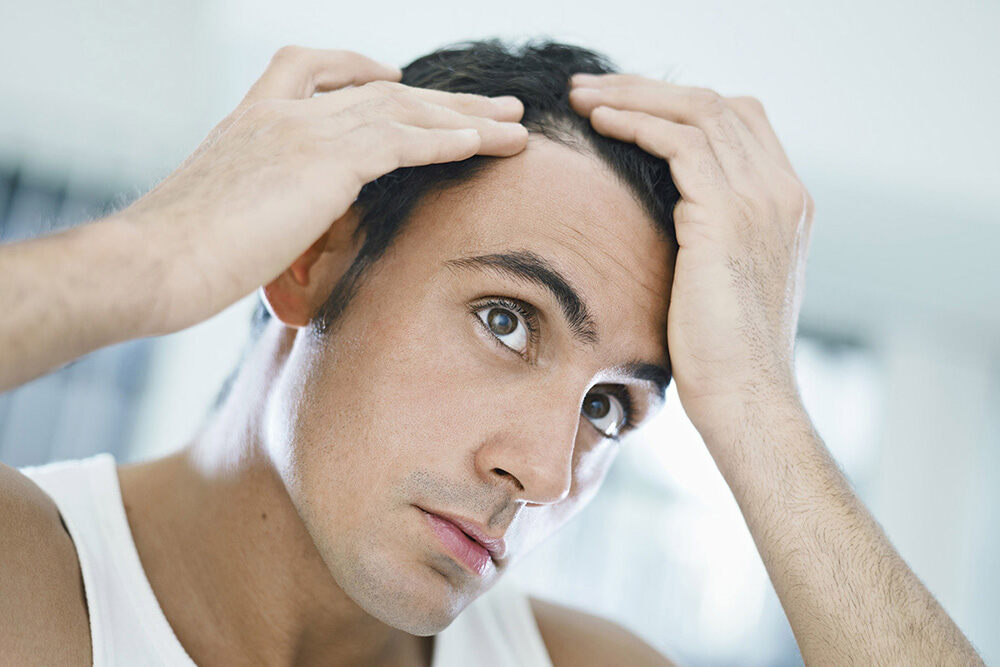 homme ayant les mains dans ses cheveux et tentant de comprendre la perte de cheveux