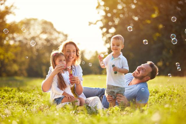 Family blowing bubbles together in a field