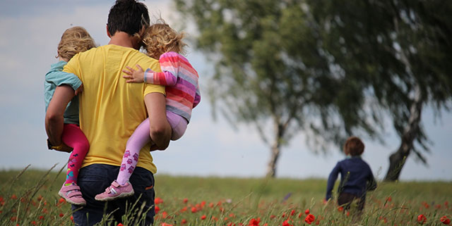 Father carrying two children