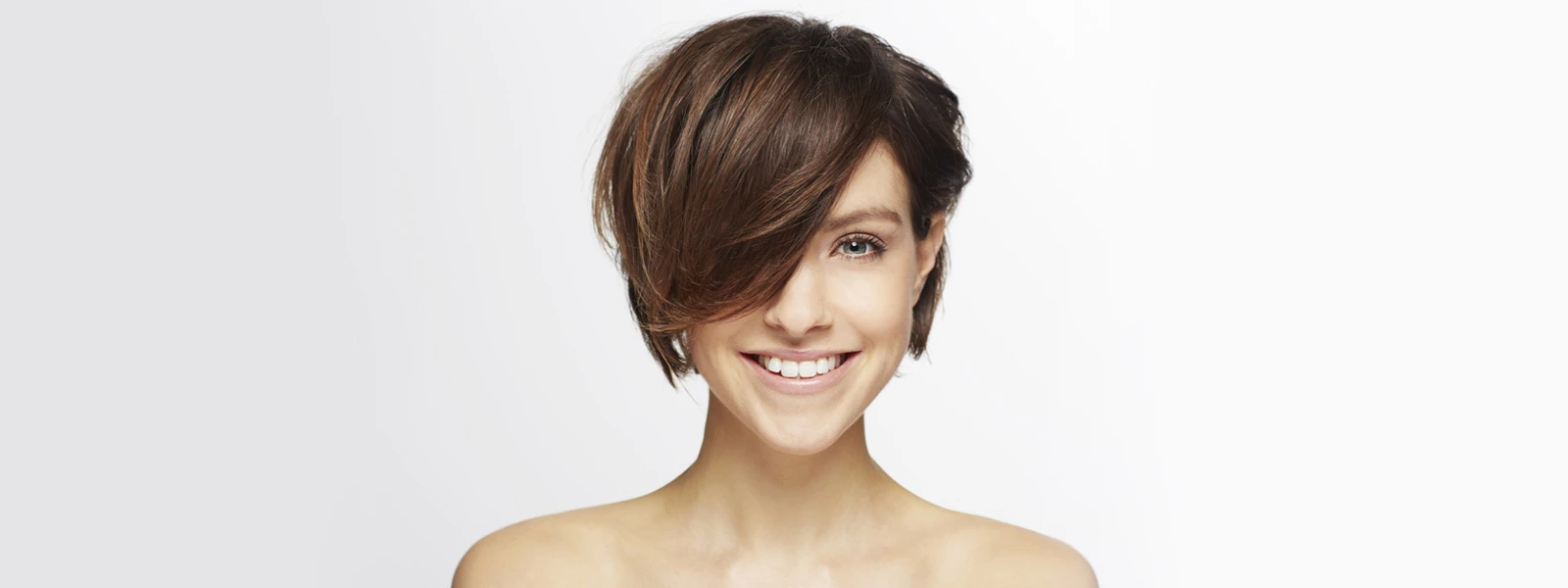 femme souriante aux cheveux bruns courts recouvrant en partie son visage