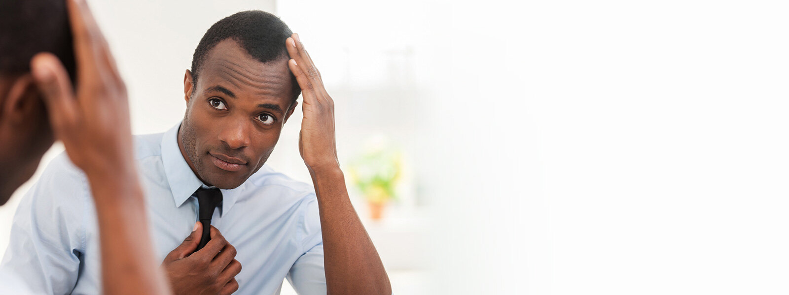 homme portant une cravate qui regarde ses cheveux dans un miroir