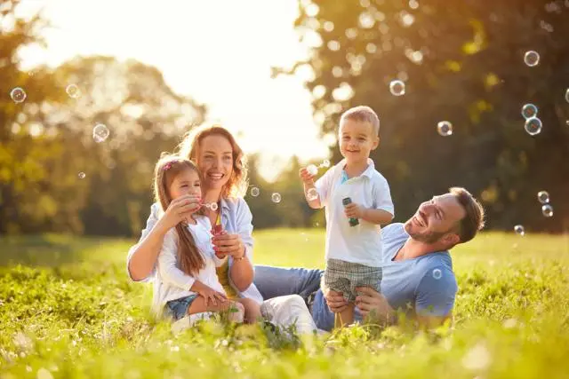 Une famille faisant des bulles ensemble dans un champ