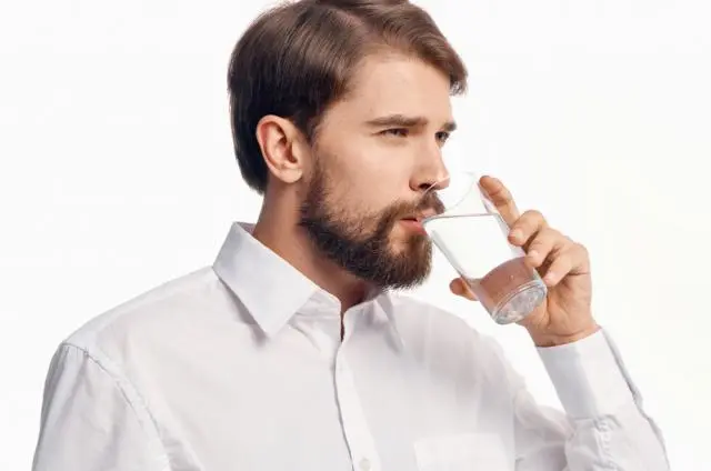 Un homme buvant un verre d’eau