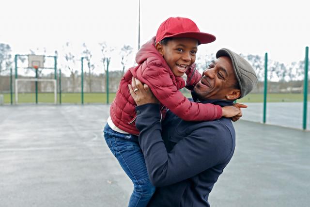 Man hold his smiling son on a basketball court