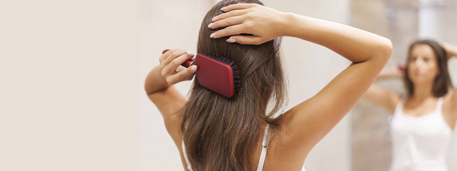 femme qui se brosse les cheveux en se regardant dans un miroir