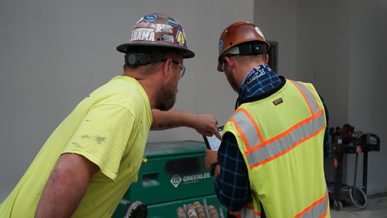 Two construction workers using a tablet