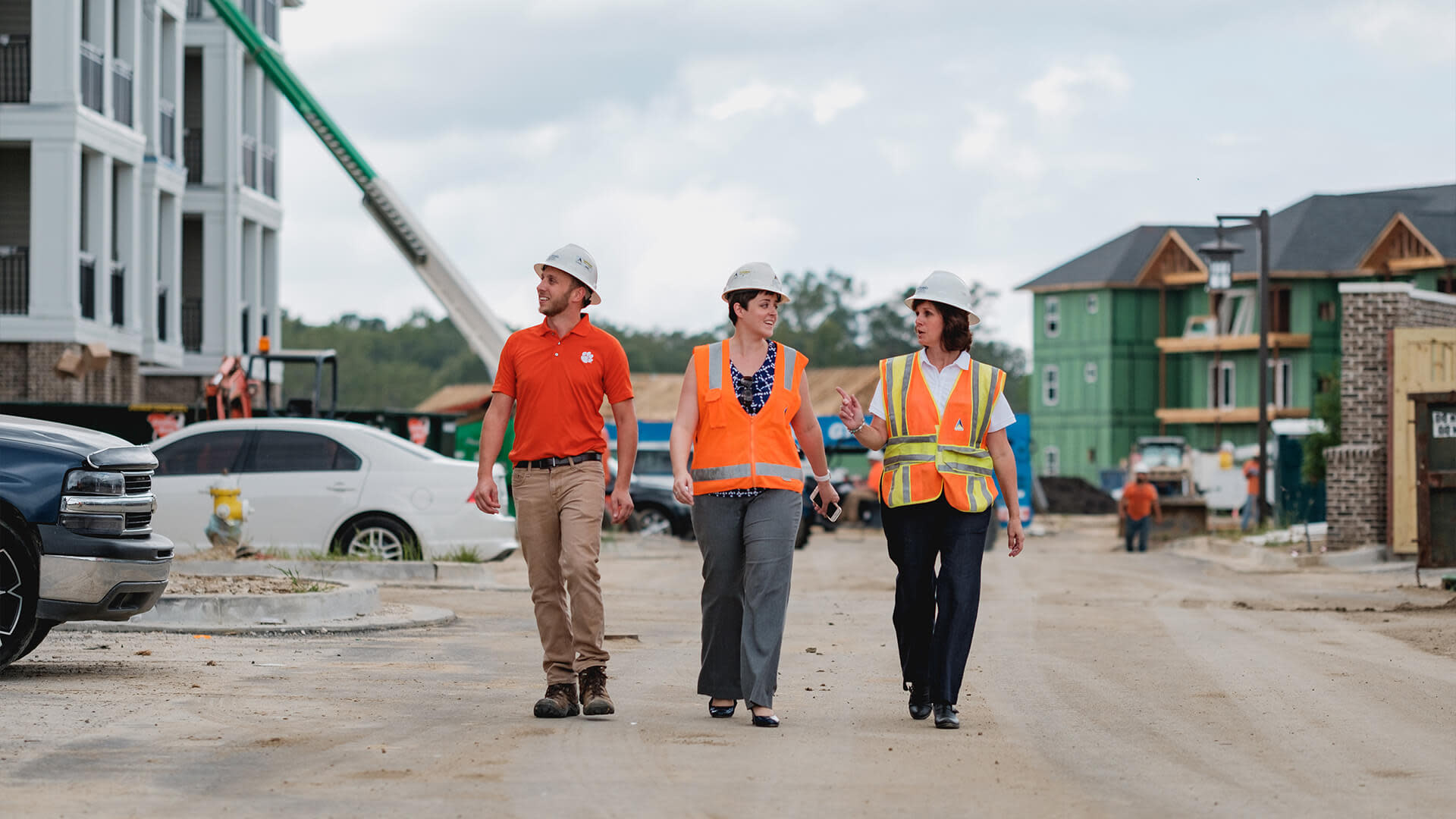 A group of people wearing safety vests and helmets walking on a construction site