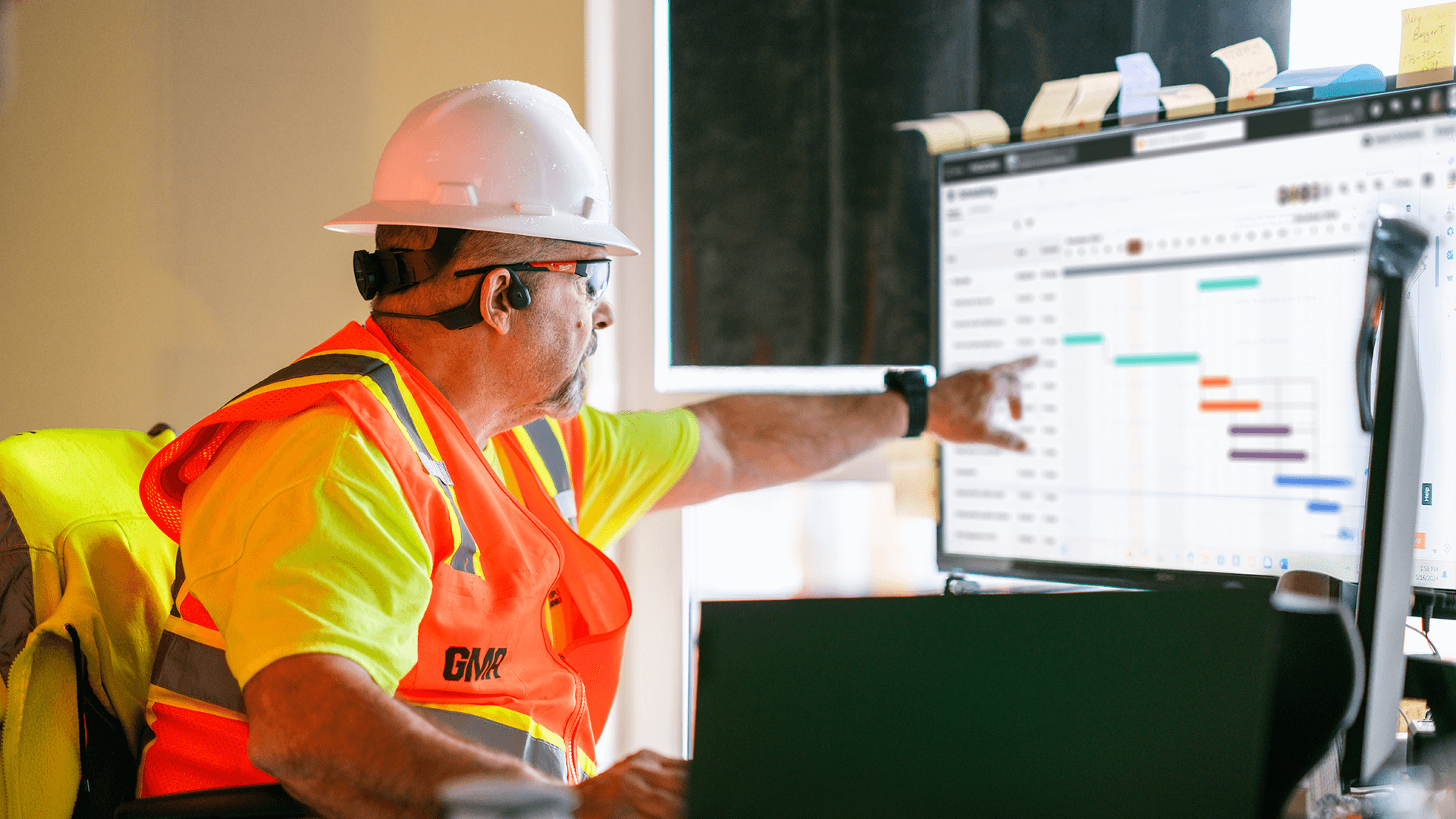 A construction worker pointing at a computer screen