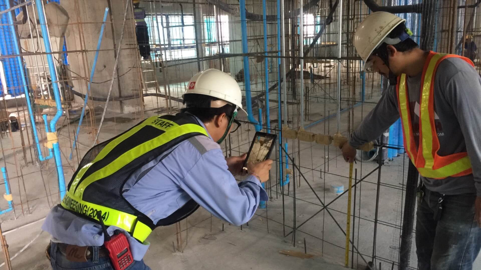 Two people using Procore to measure fittings.