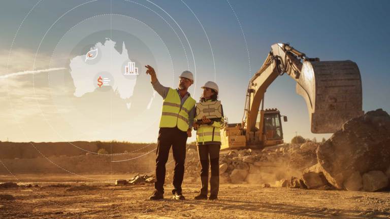 two construction workers wearing safety vests and helmets standing in front of a construction site