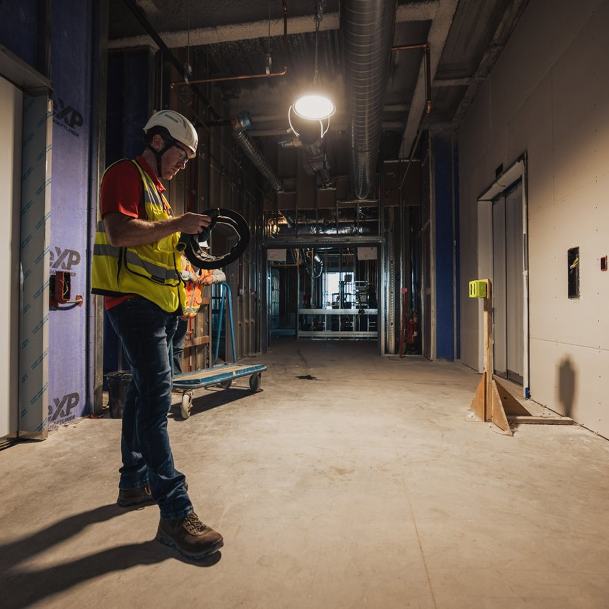 Construction worker in safety gear inspecting equipment inside a building site.
