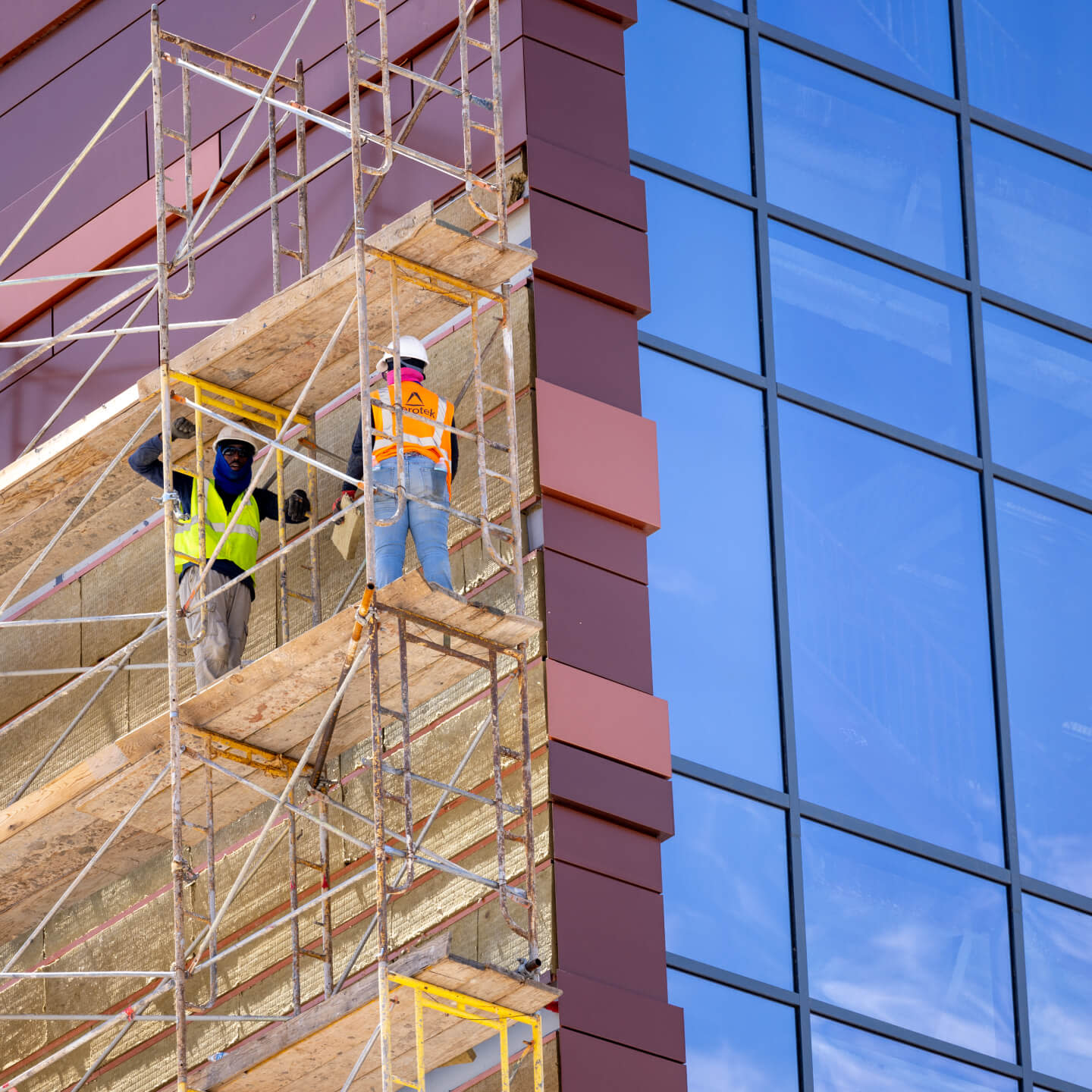 Two construction workers standing on a scaffold