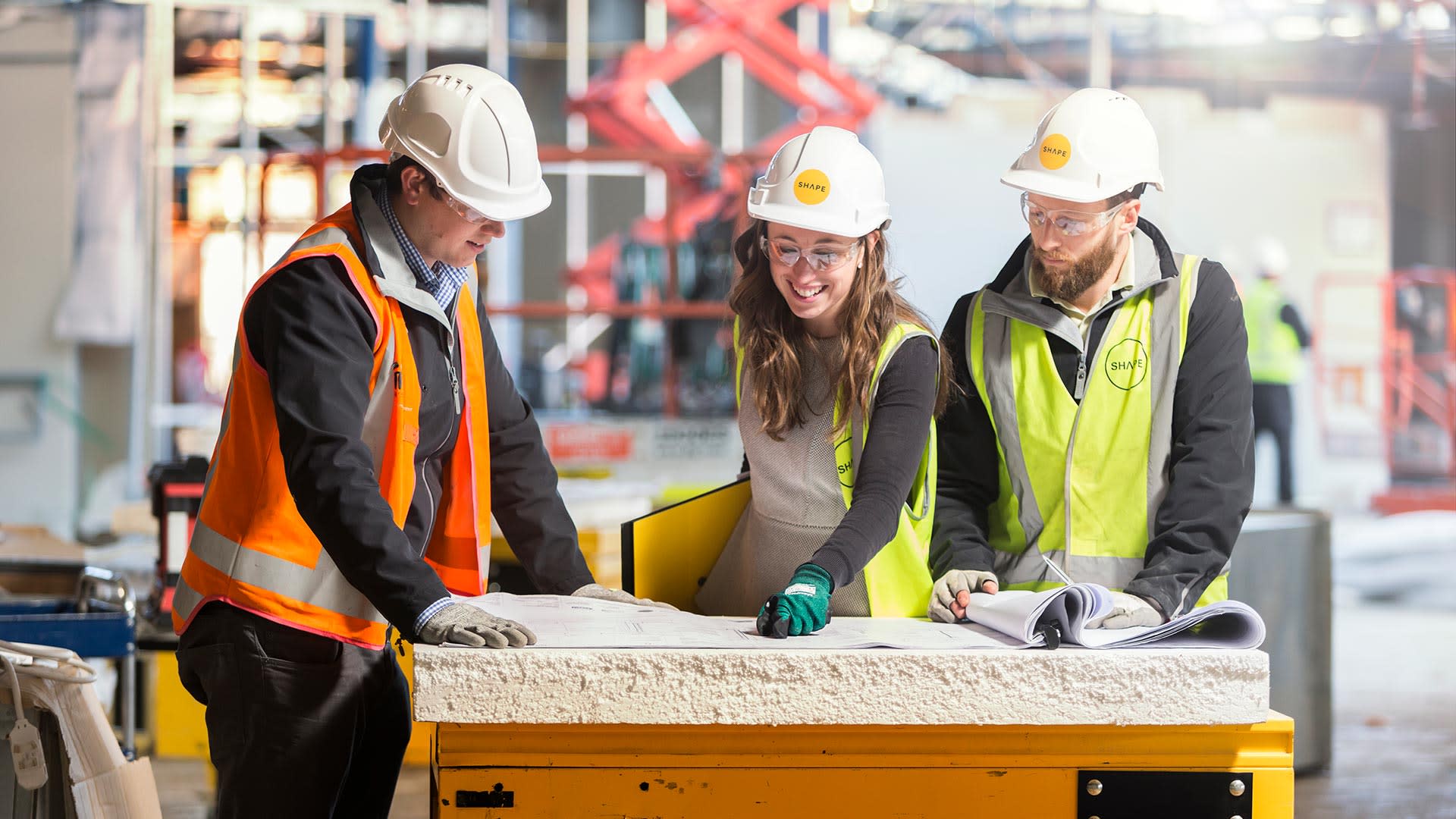 Three contractors talking over blueprints