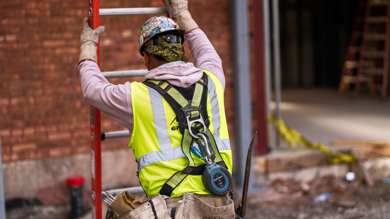 A construction worker moving a ladder