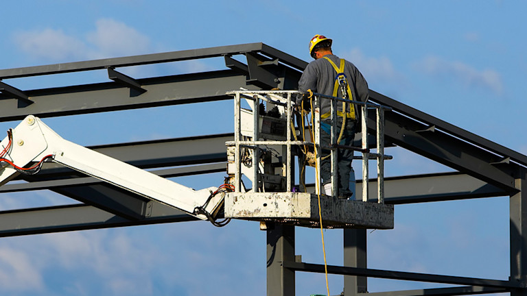 worker using a lift to work on a metal framework of a building