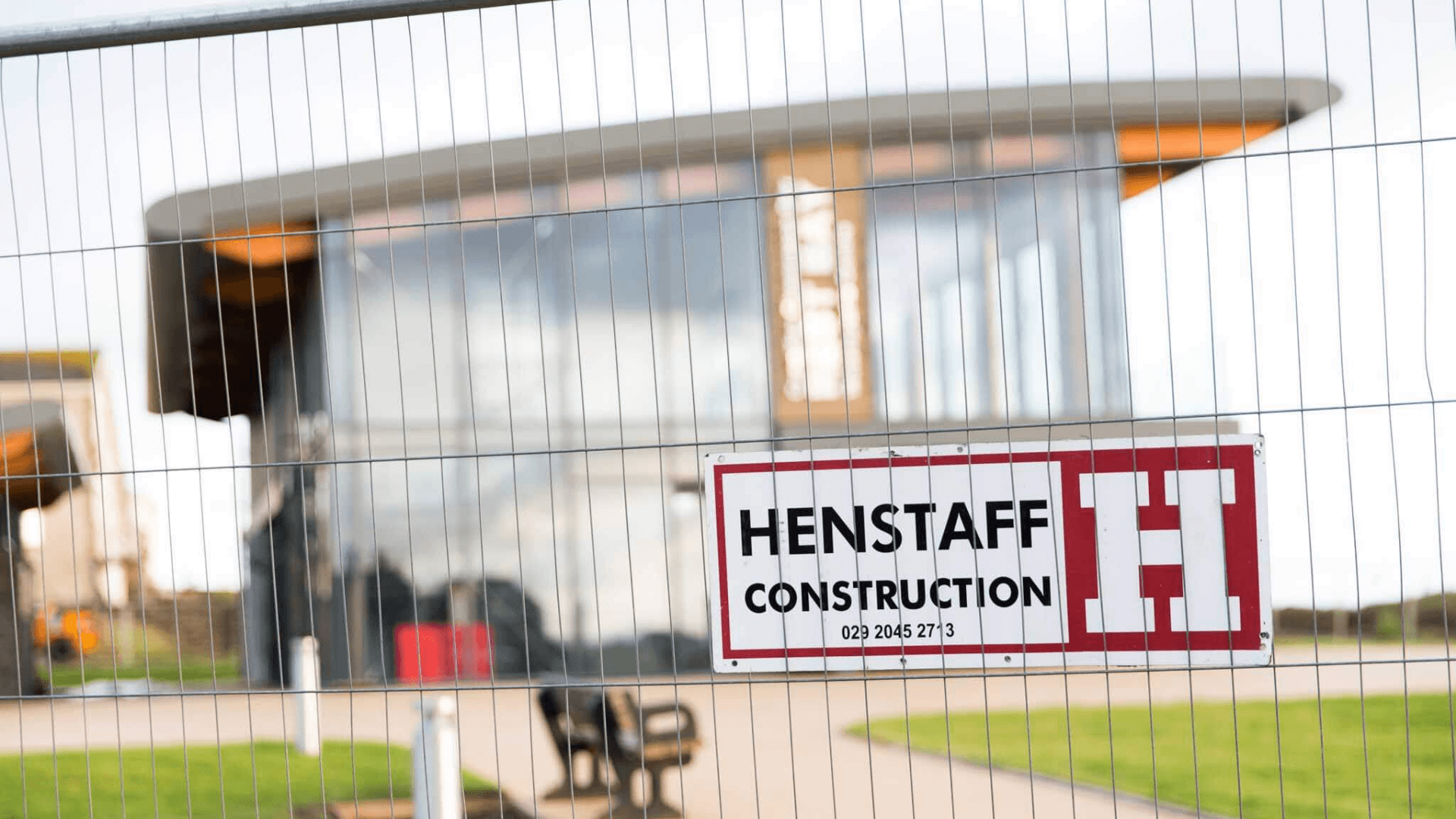 Henstaff Construction's plaque in a mesh and a building behind it