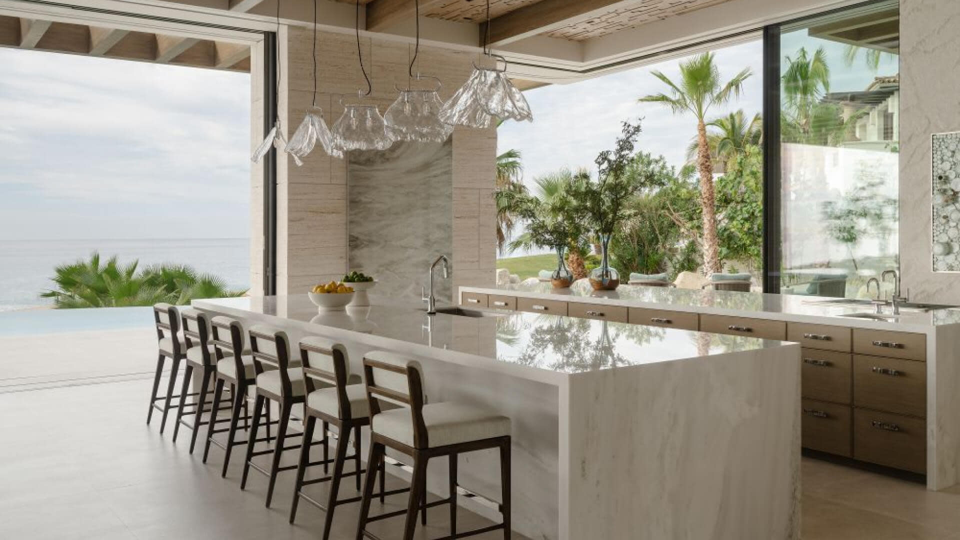 Modern kitchen with a large island, offering a view of the ocean through large windows.