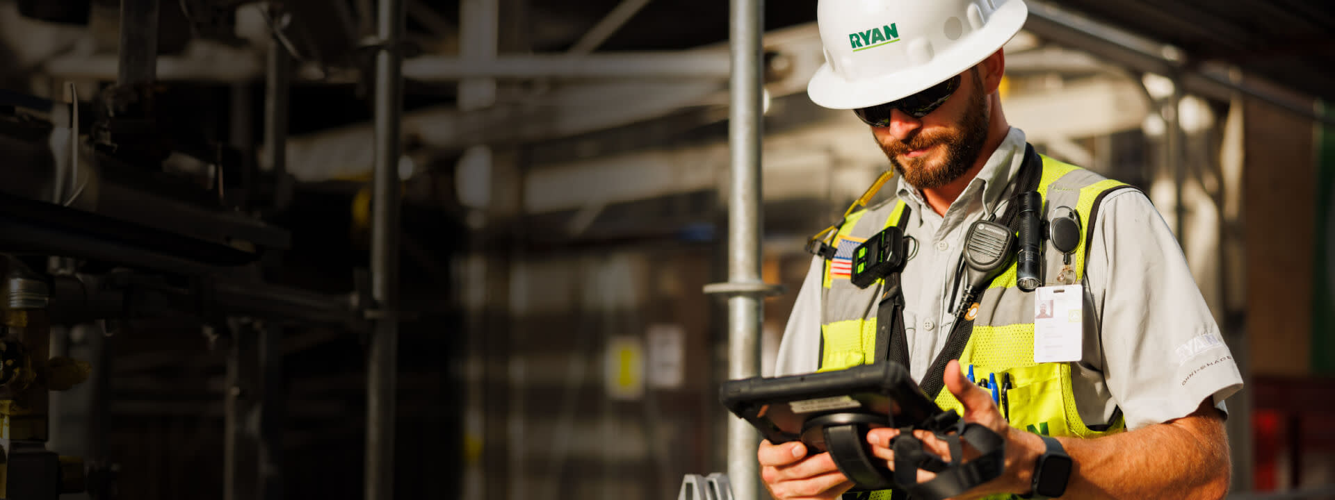 A man wearing safety gear using a tablet on site