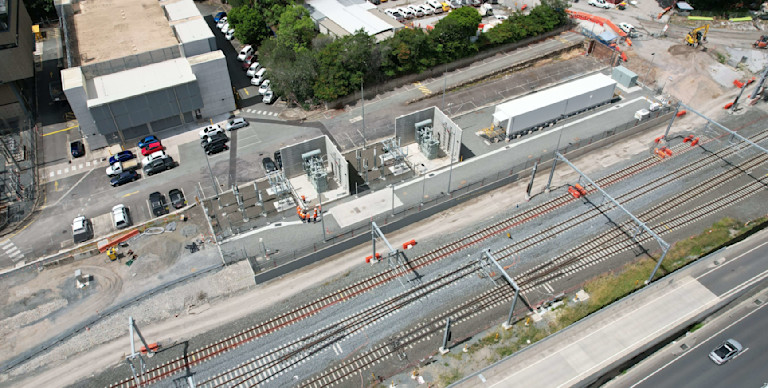 Aerial view of railway tracks, construction site, and parked vehicles near buildings.