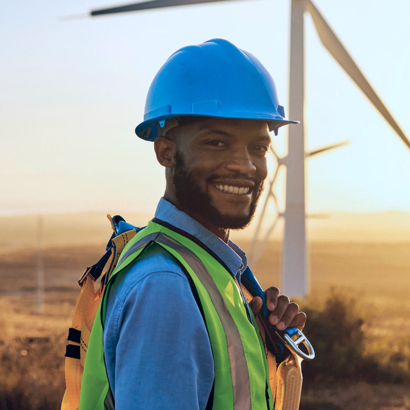 construction worker in front of a wind farm wearing ppe