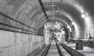 Empty underground train tunnel with tracks and overhead lighting.