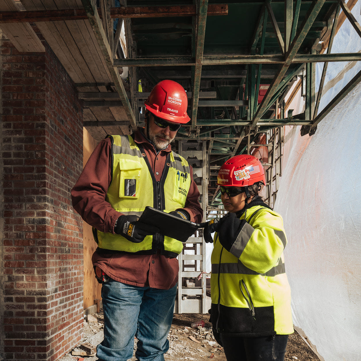 Two construction workers using a tablet on site