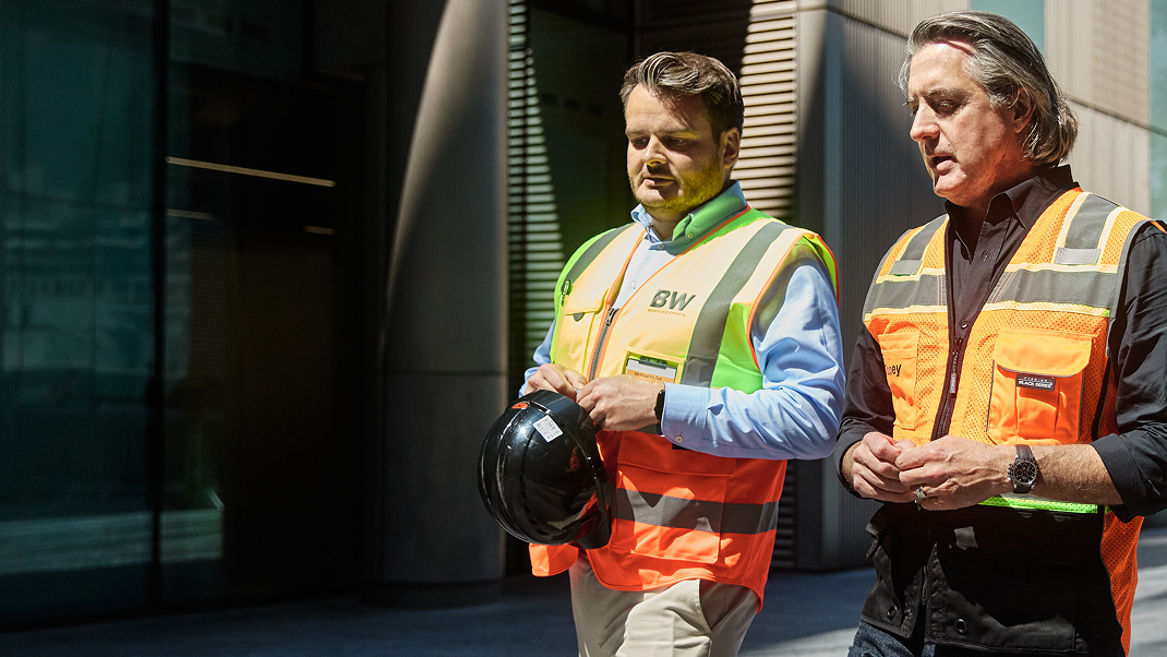 Procore's founder and CEO walking next to a contractor, both wearing a safety vest