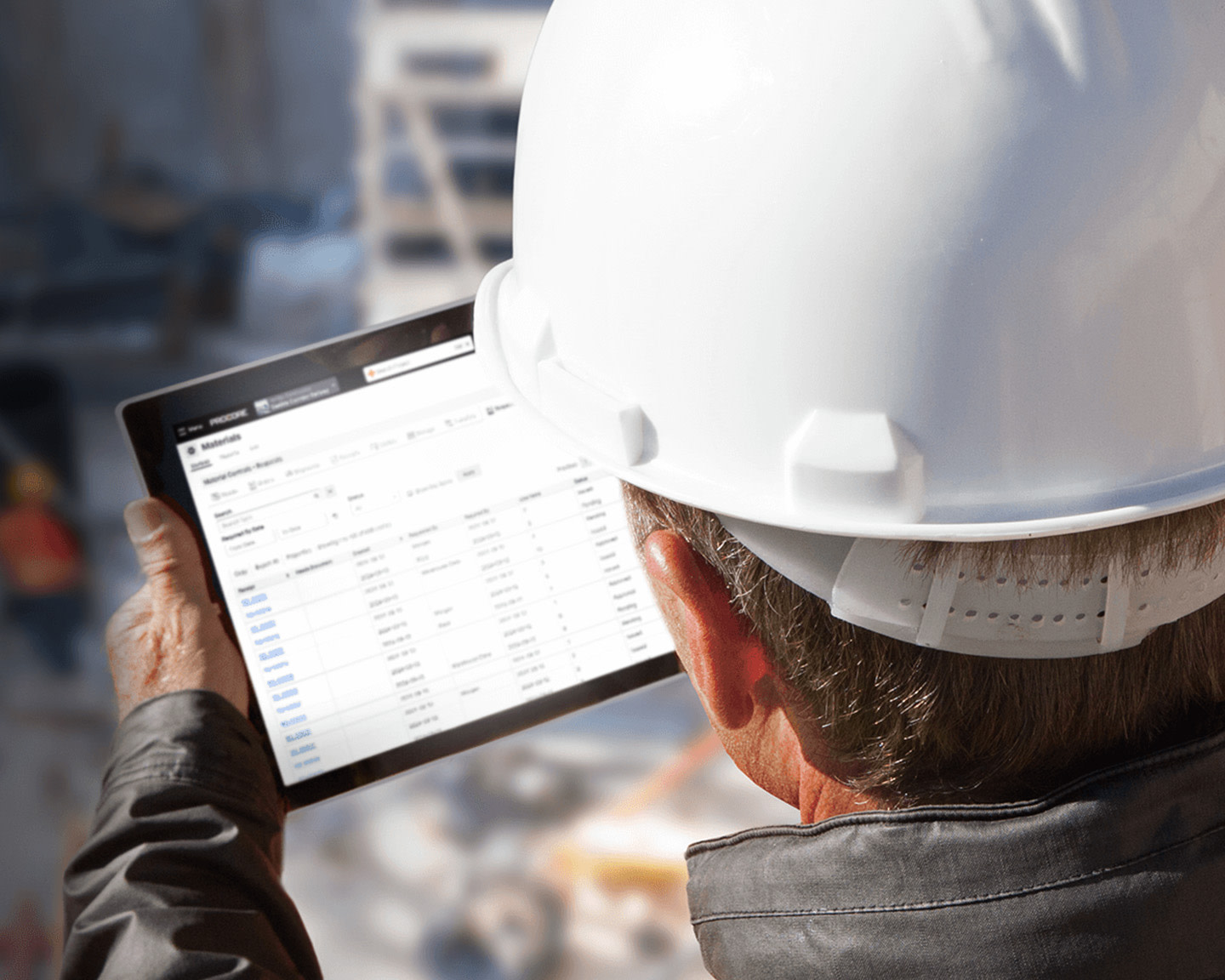 A construction worker using a tablet, looking down at a jobsite