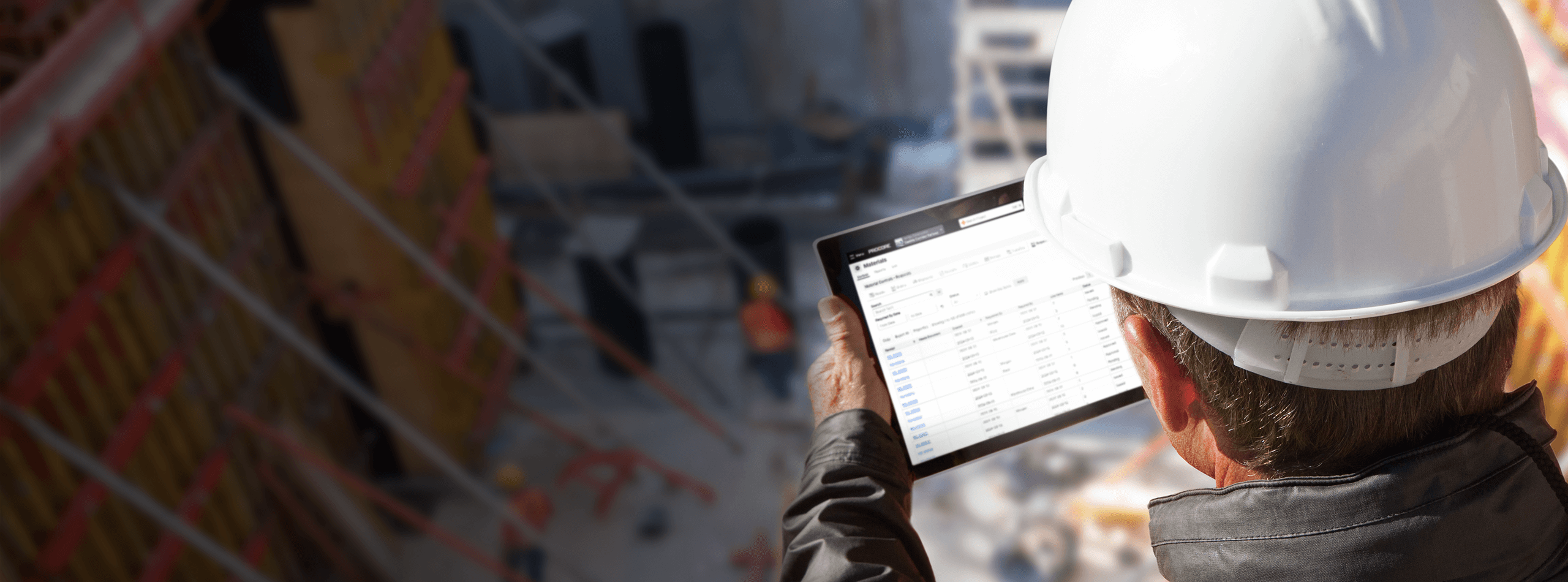 A construction worker using a tablet, looking down at a jobsite