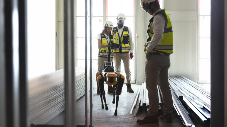 Three construction workers standing around a robot