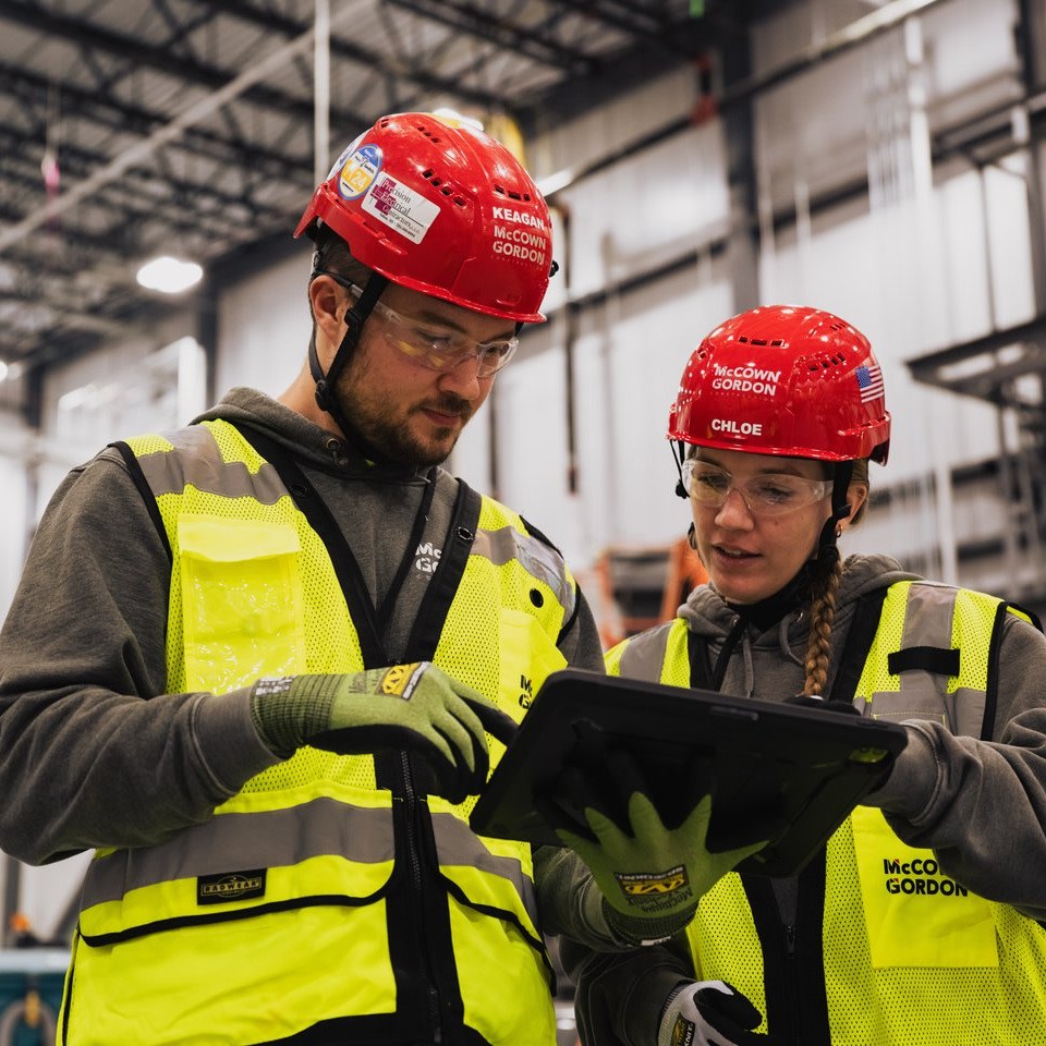two construction workers looking at a tablet