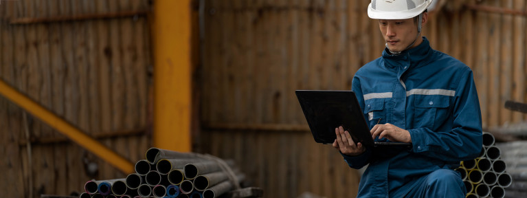 A man wearing safety gear and working on a laptop