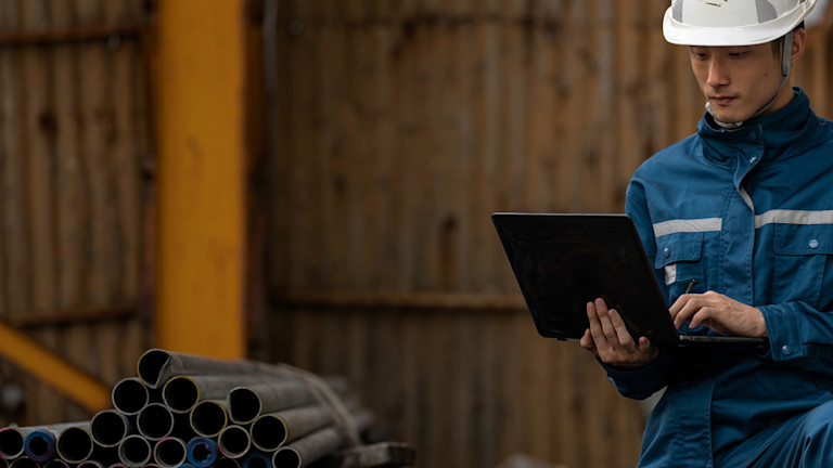 A man wearing safety gear and working on a laptop