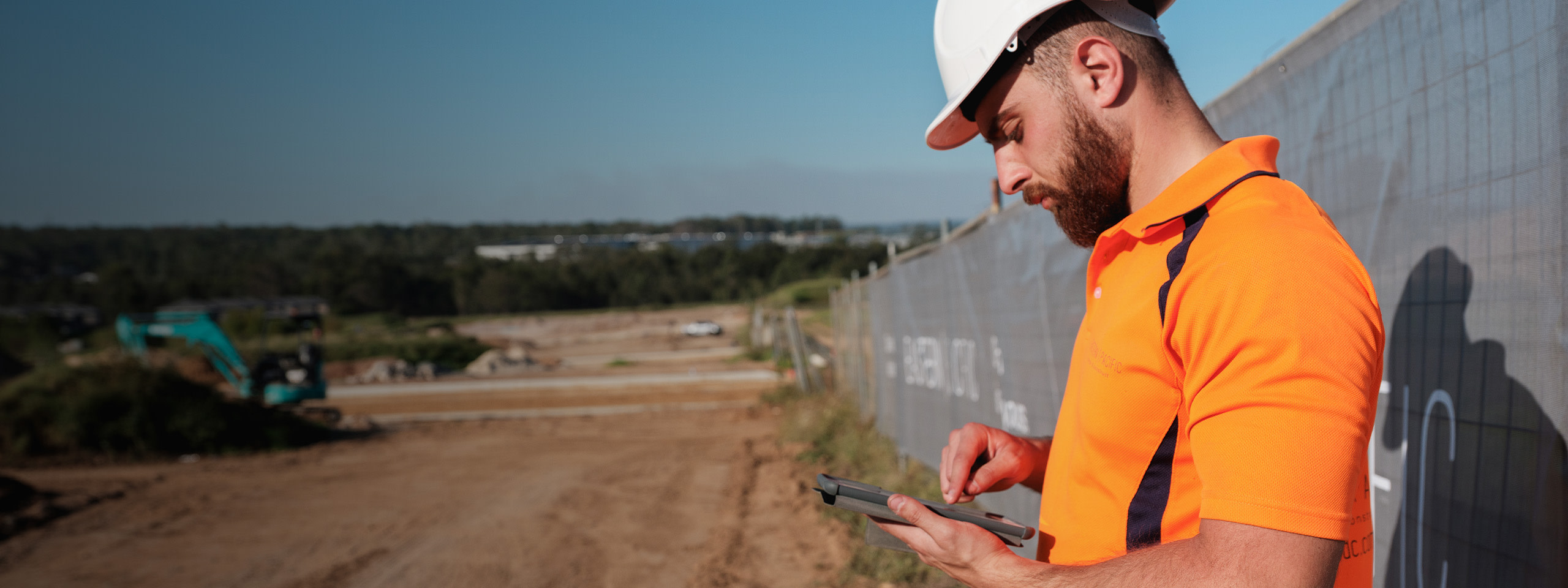 a person in a hard hat using a tablet in an open area