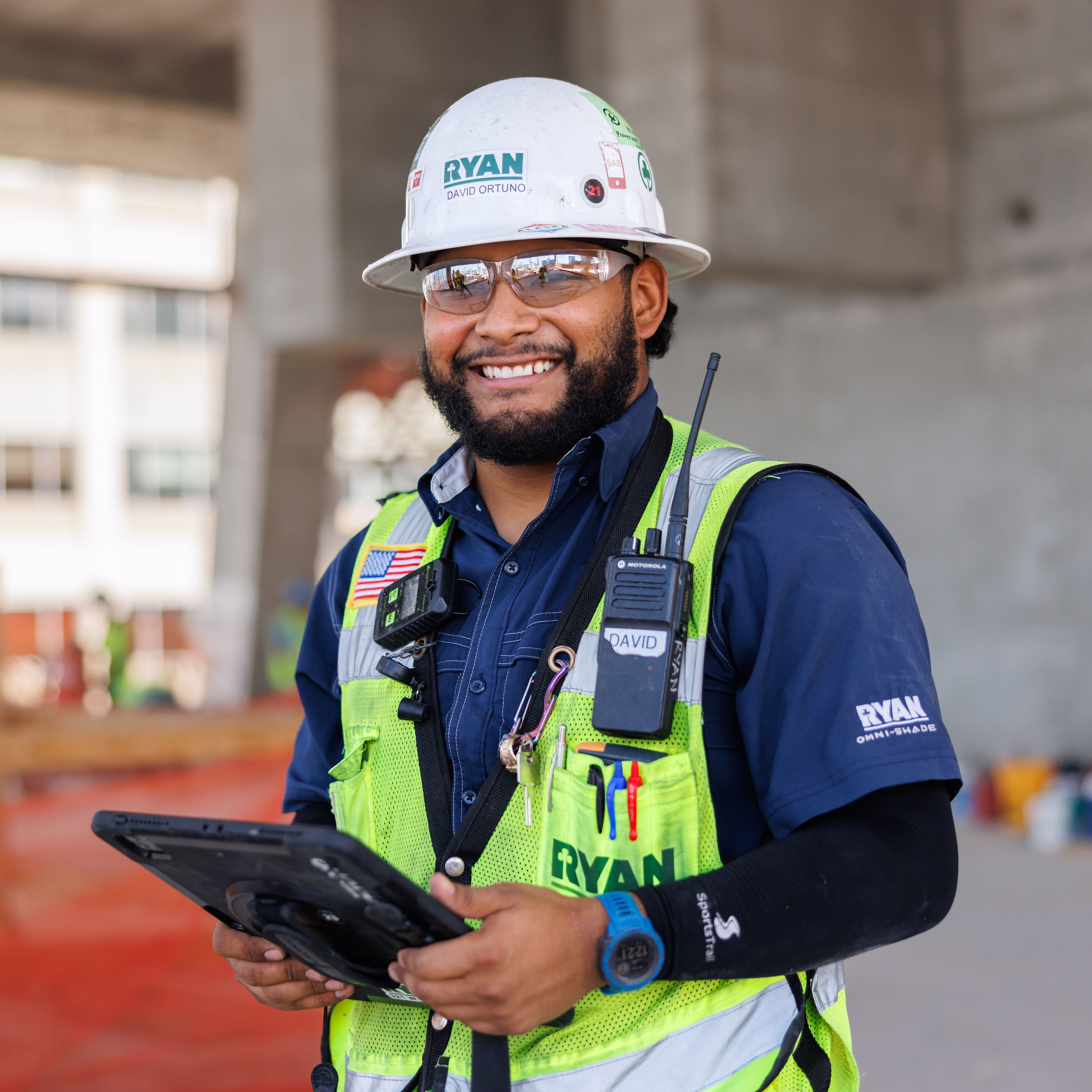 A construction worker holding a tablet at a construction site