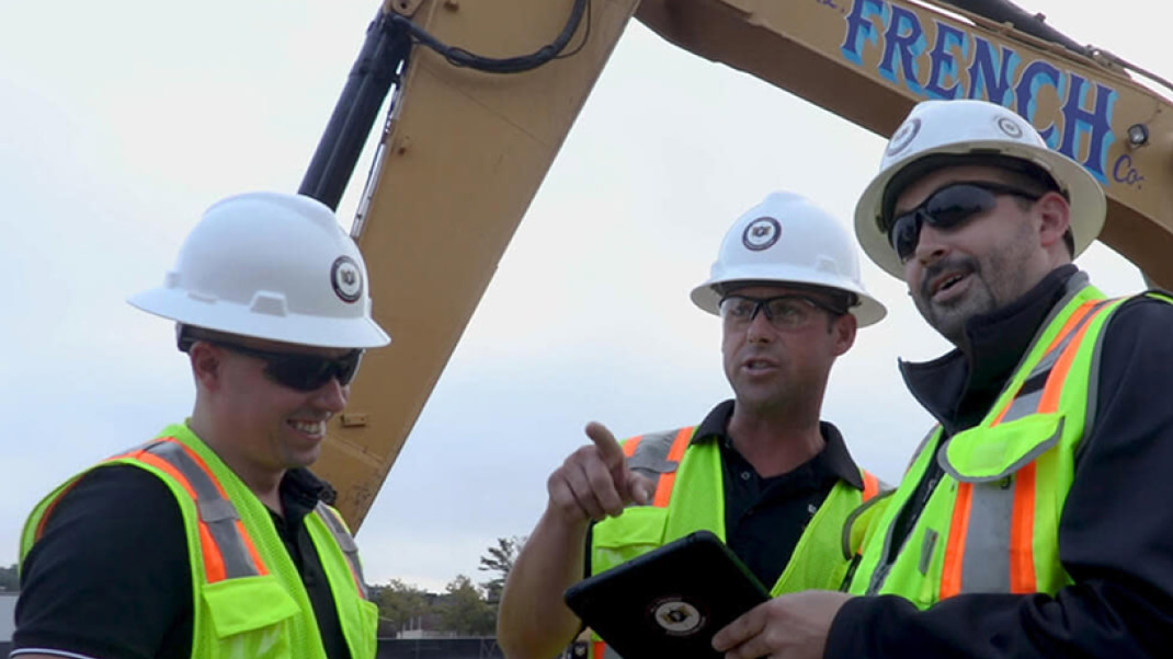 Contractor's using Procore on a tablet pointing to an area of the construction site
