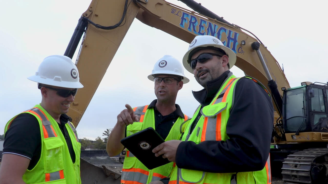 Contractor's using Procore on a tablet pointing to an area of the construction site