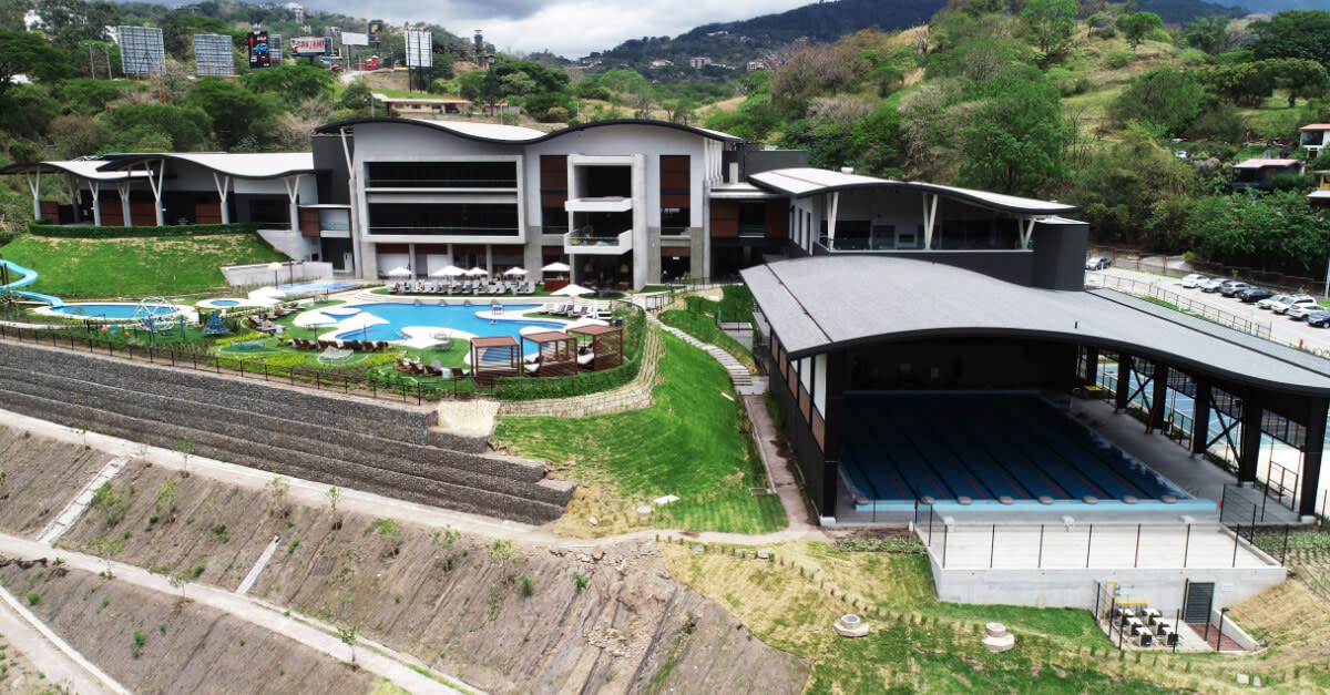 Centro deportivo moderno con piscinas al aire libre y techada en zona montañosa