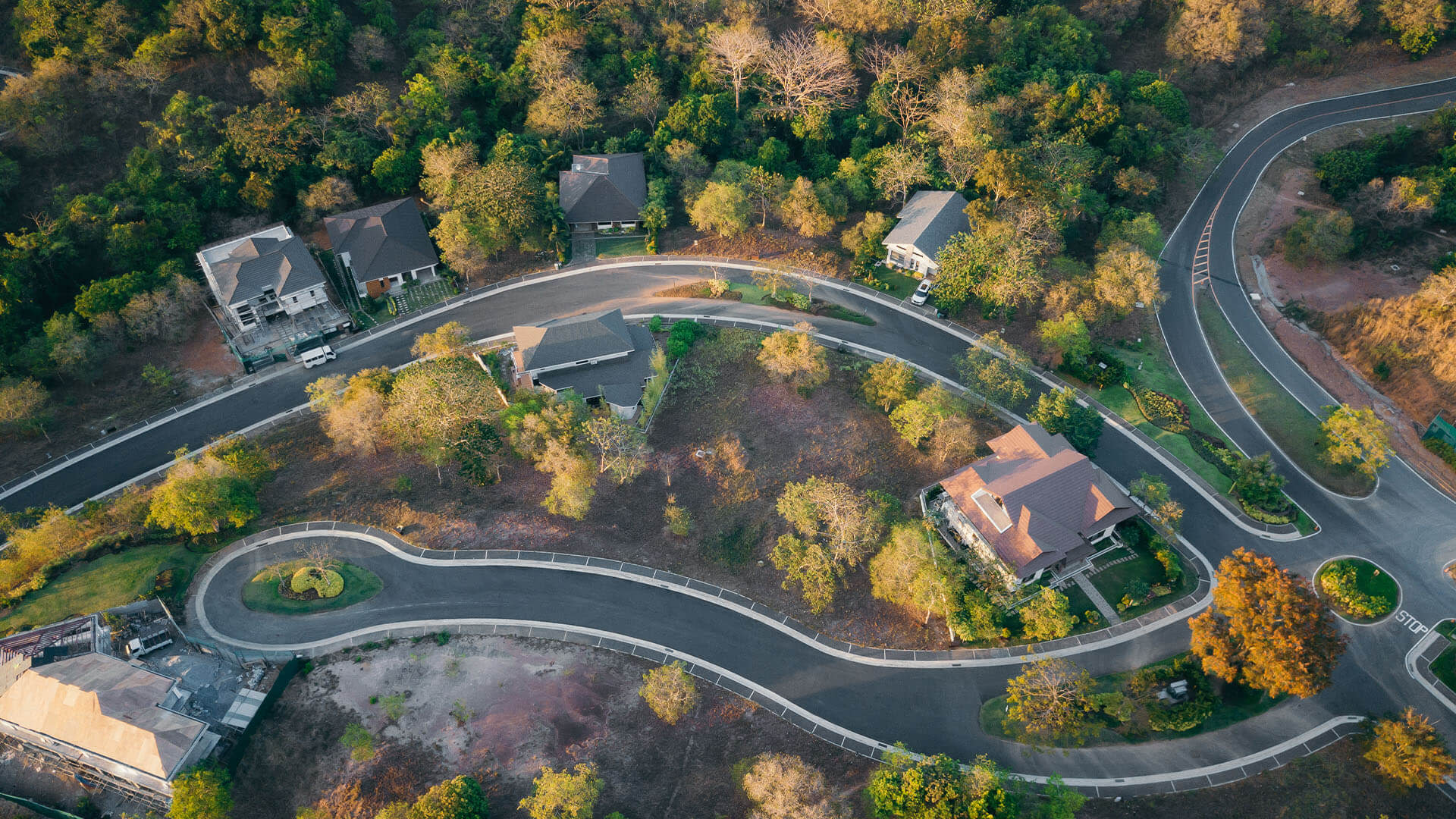 Aerial view of curved suburban street with houses and autumn trees